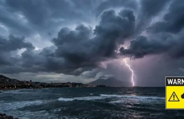 Cielo minaccioso con nubi scure e fulmini sopra il golfo di Napoli durante un'allerta meteo.